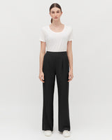 Woman standing in a T-shirt and trousers, facing forward.