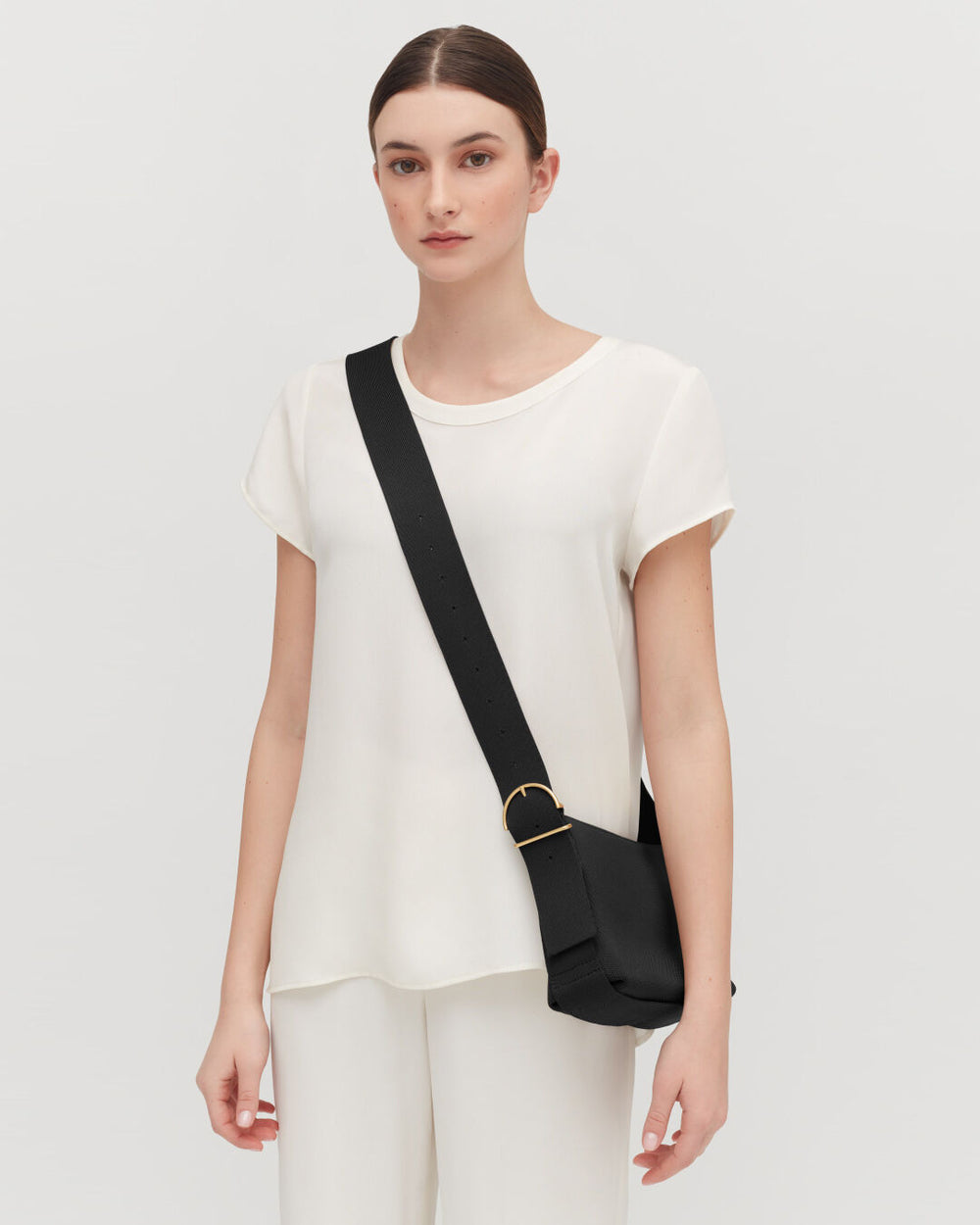 Woman standing with a shoulder bag.