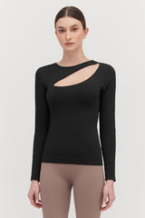 Woman in a long-sleeve top with an asymmetrical neckline, standing.