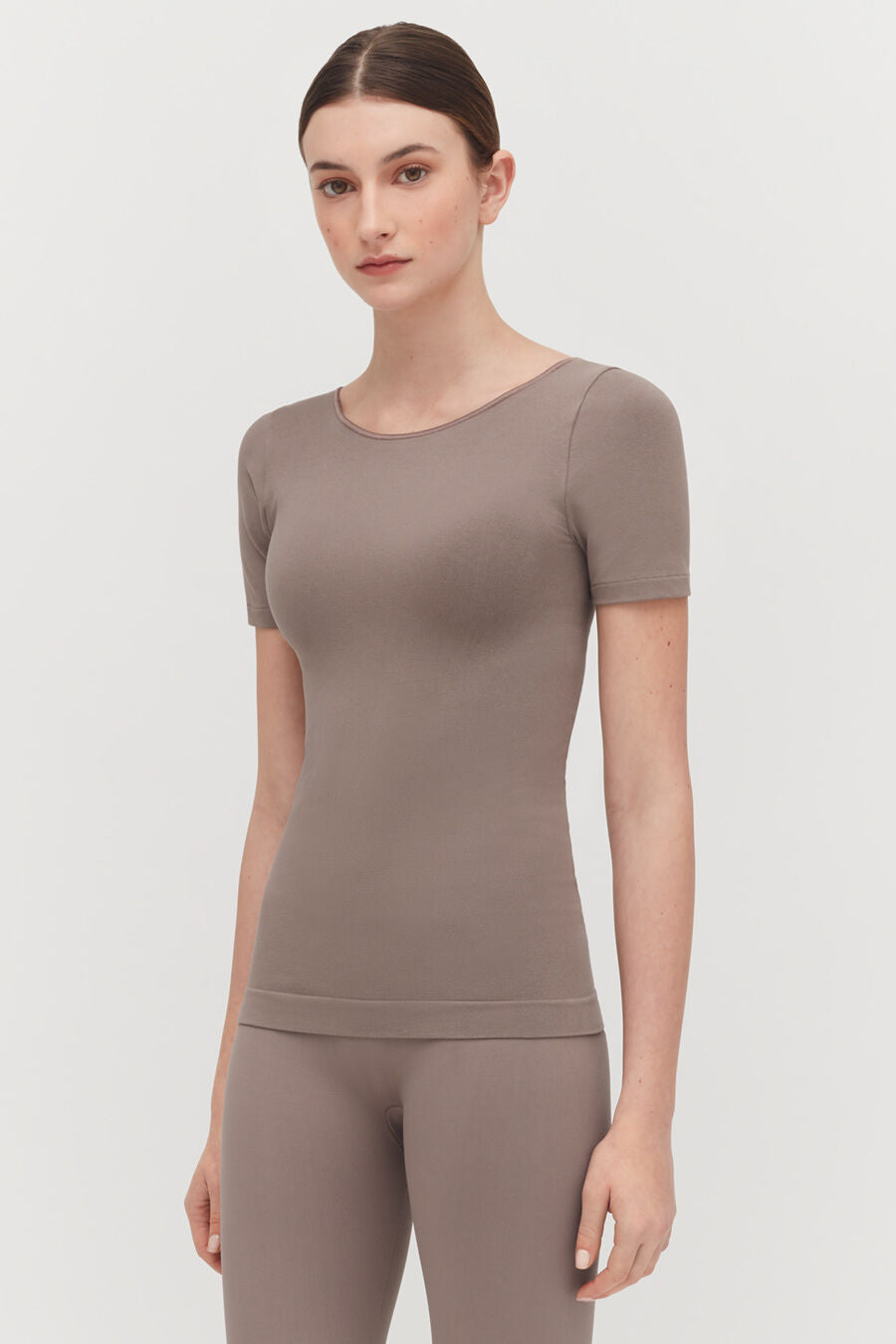 Stretch Scoop Neck Tee Woman standing in a short-sleeved top and leggings, looking at camera.