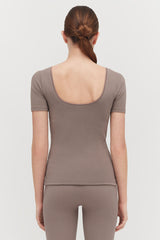 Woman viewed from behind with a ponytail hairstyle wearing a short sleeve top and leggings.