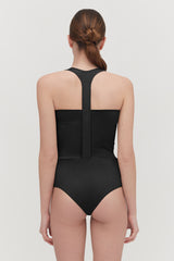 Woman from behind wearing a sleeveless swimsuit with a high neckline.