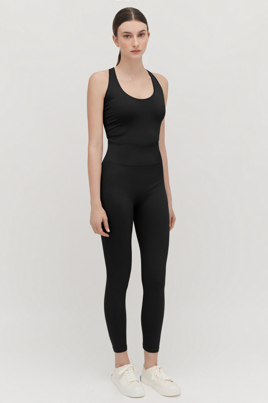 Stretch Tank Bodysuit Woman standing in a tank top and leggings, facing forward.