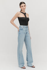 Woman standing in black top and blue jeans with hands by sides.