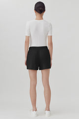 Person standing facing away, wearing a short-sleeved top and shorts.