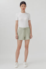 Woman standing in a t-shirt and shorts with sneakers.