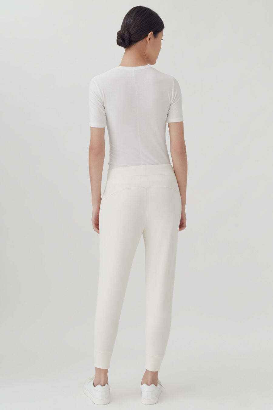 French Terry Tapered Lounge Pant Woman standing with her back towards the camera in a plain outfit.