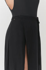 Person seen from the back wearing a fitted top and skirt with a slit.