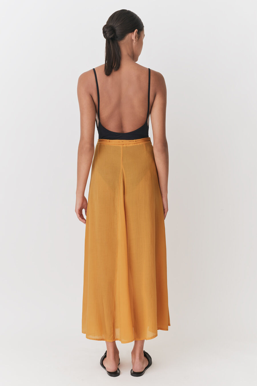 Wrap Maxi Cover Up Woman viewed from behind wearing a tank top and long skirt, standing upright.