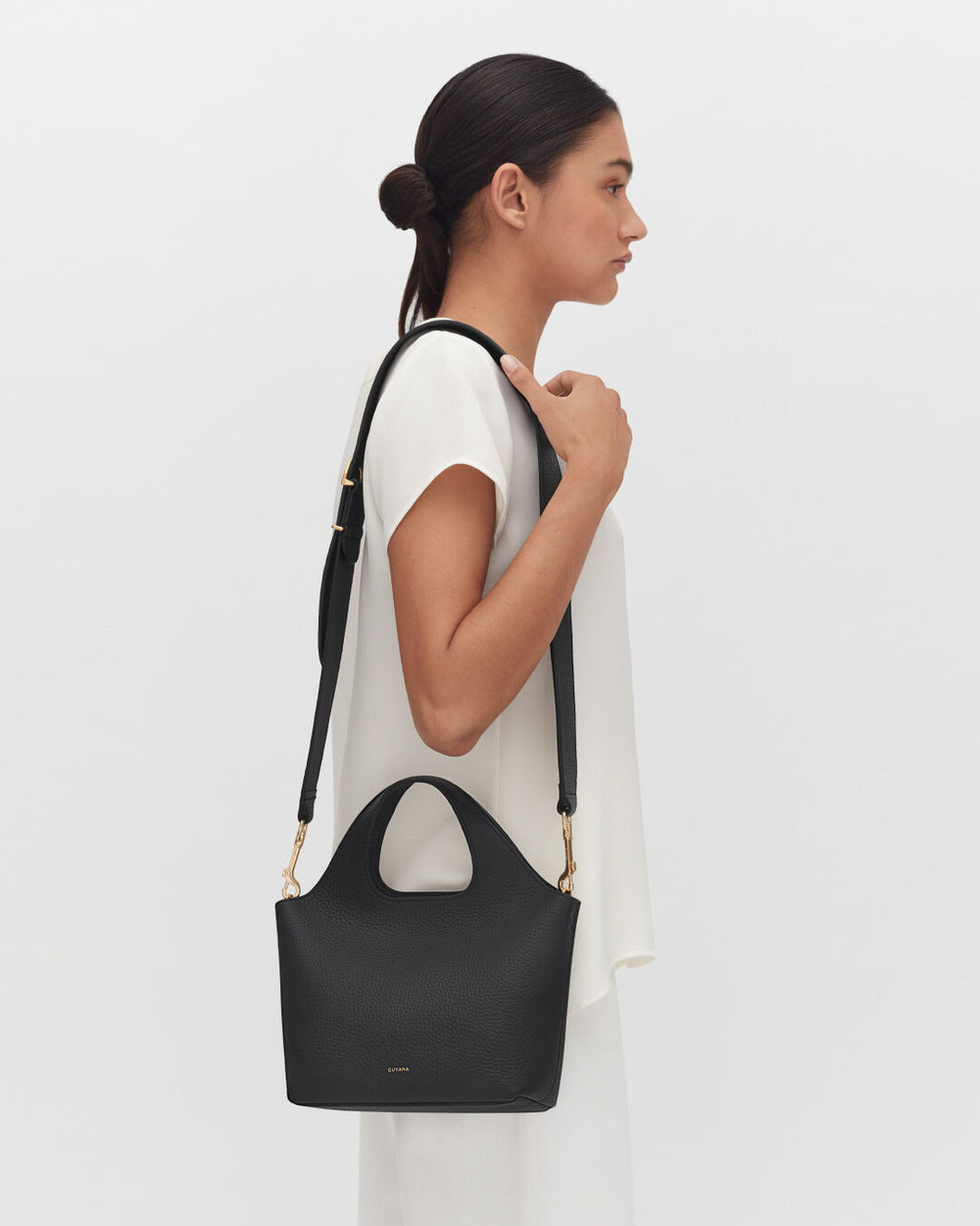 Woman with bag over shoulder looking to the side.