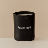 Scented candle with labeled text, on a plain background.