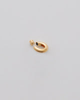 Earring in the shape of an abstract figure on a light background.