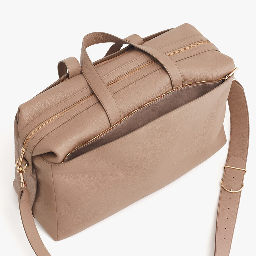 Overhead view of a closed travel bag with a shoulder strap and handles.