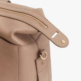 Close-up of a backpack with a zipper and a metal ring on a strap.
