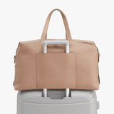 Bag resting on top of a suitcase handle