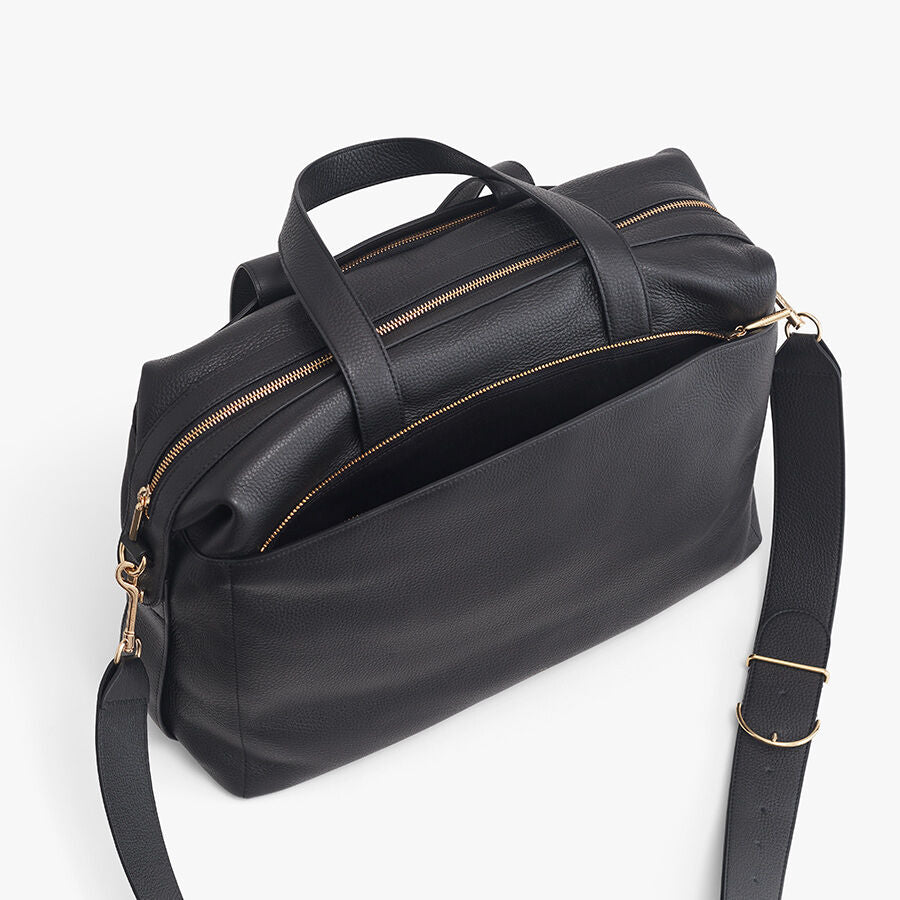 Travel bag with handles and shoulder strap on a plain background