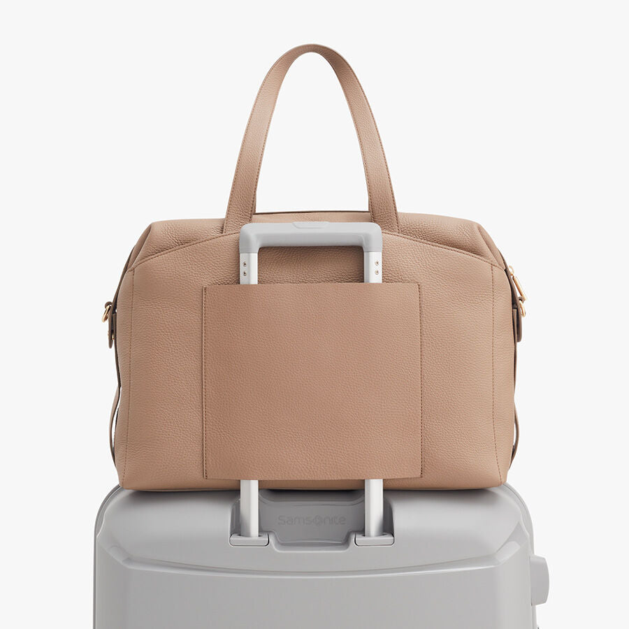 Overnight Bag Handbag placed on top of a suitcase handle.