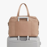 Handbag placed on top of a suitcase handle.