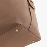 Close-up of a bag corner with metal studs and textured fabric.