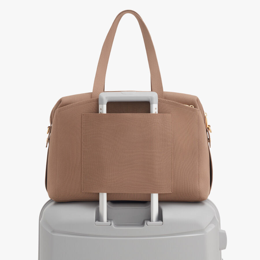 Handbag on top of a suitcase handle.
