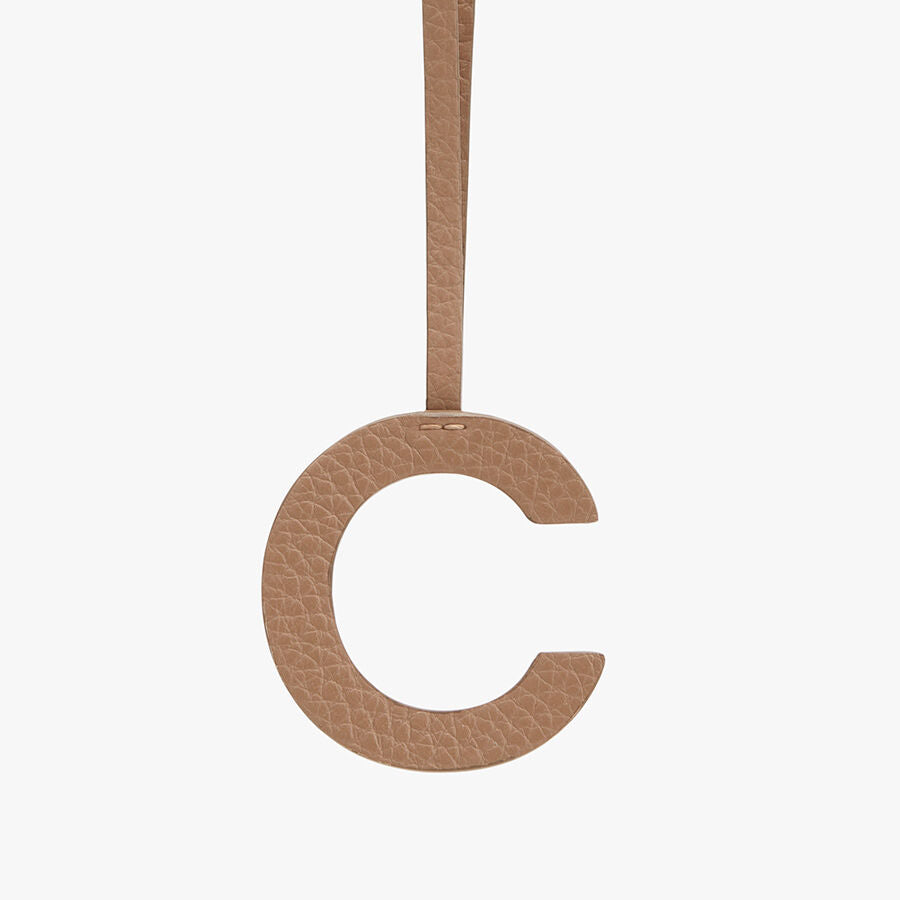 Letter C hanging from a strap against a plain background.