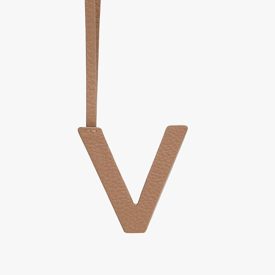 Letter V hanging from a strap on a plain background.