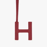 Letter H hanging by a strap against a plain background.