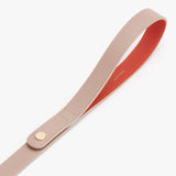 A leather strap with a snap fastener and embossed brand name.