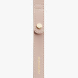 Close-up of a strap with stitched edges and a metal snap button.