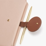 Close-up of a pen and notebook secured by a strap.
