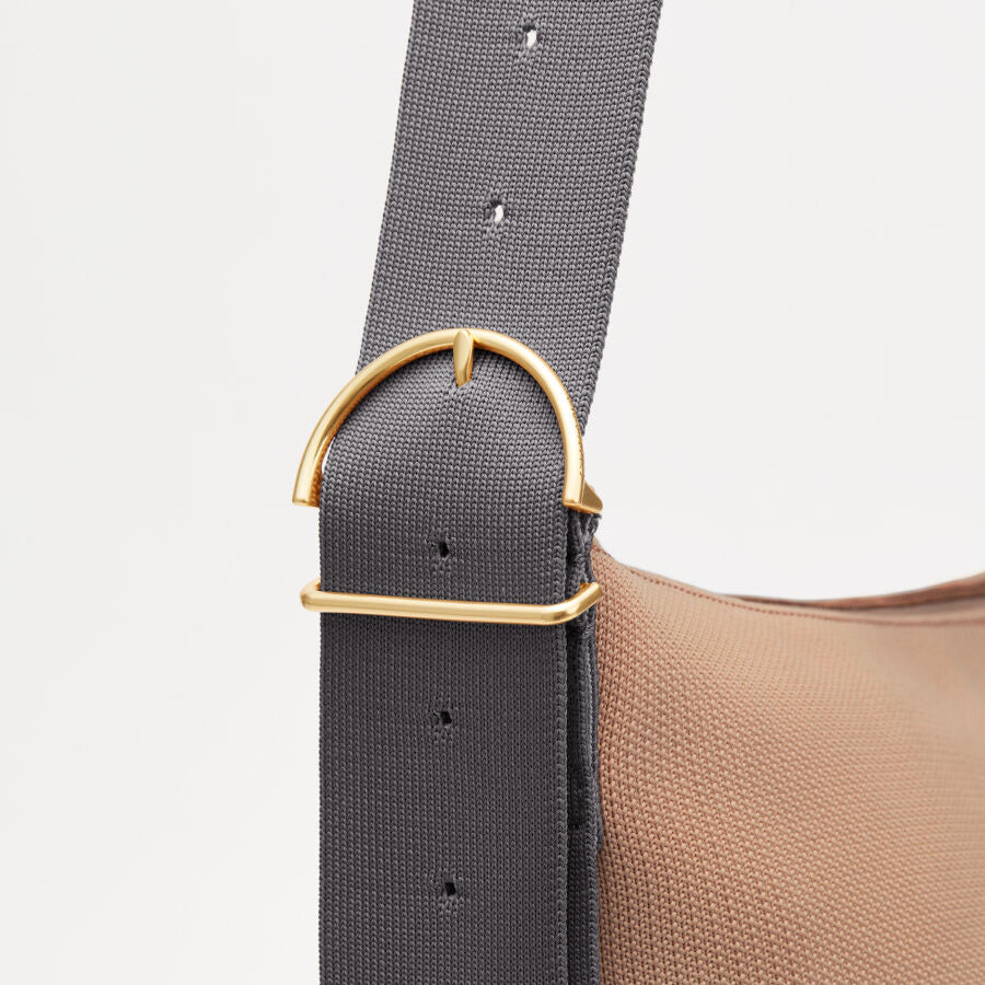Close-up of a strap attached to a bag with a metal buckle.