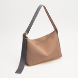 Handbag with a long, adjustable strap on a plain background.