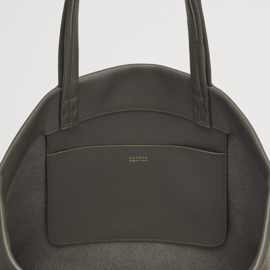 Close-up view of a handbag with a front pocket and brand logo.