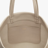 Close-up of a handbag with two handles and a front pocket.