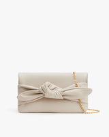 Clutch purse with a bow and chain strap on white background.