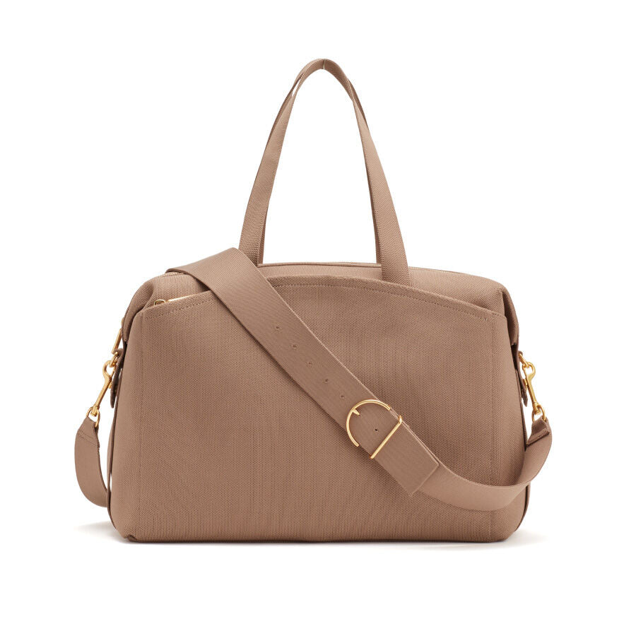 Handbag with top handles and a shoulder strap, standing on a flat surface.