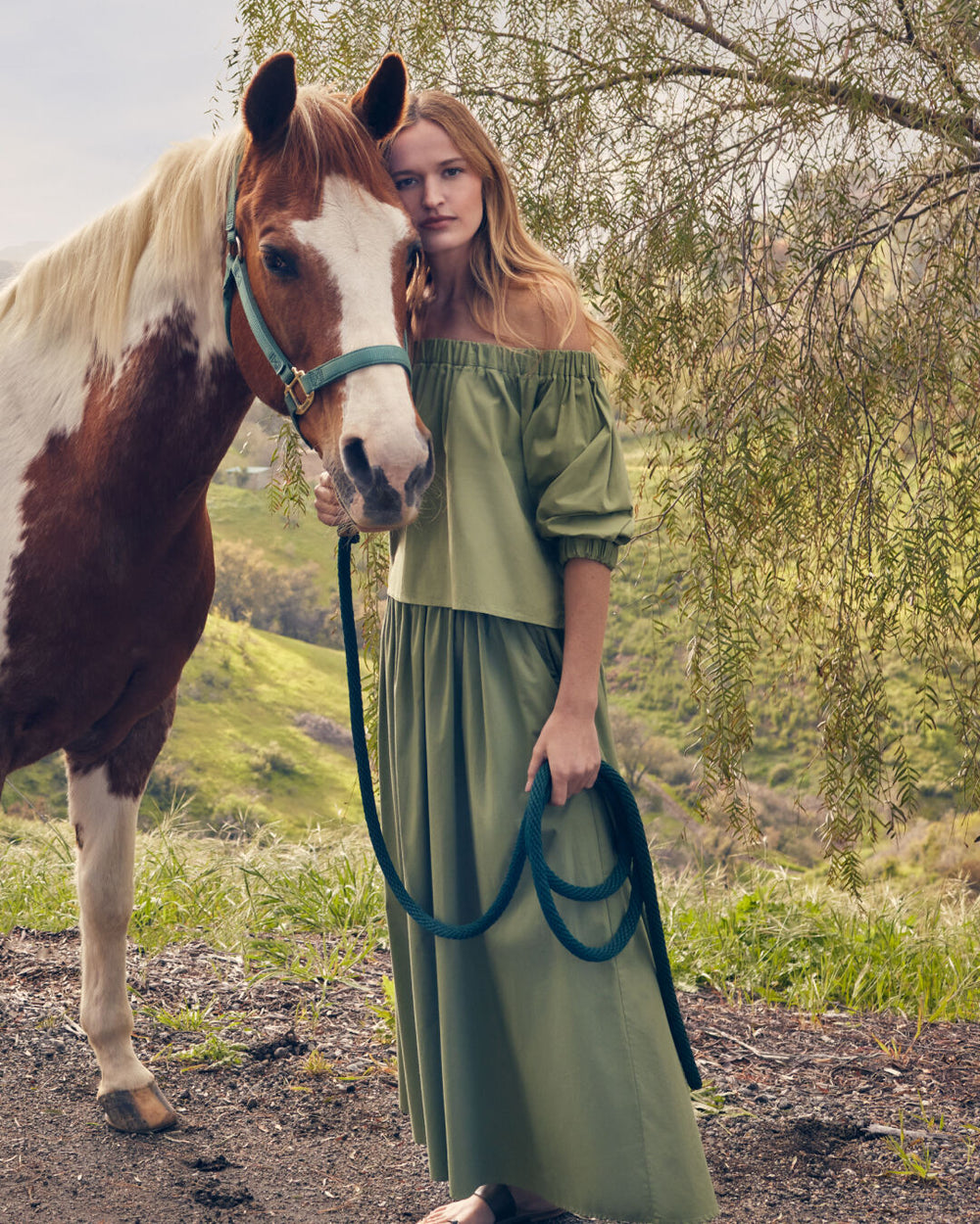 Woman standing next to a horse outdoors.