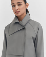 Woman in a high-collared jacket looking at the camera.