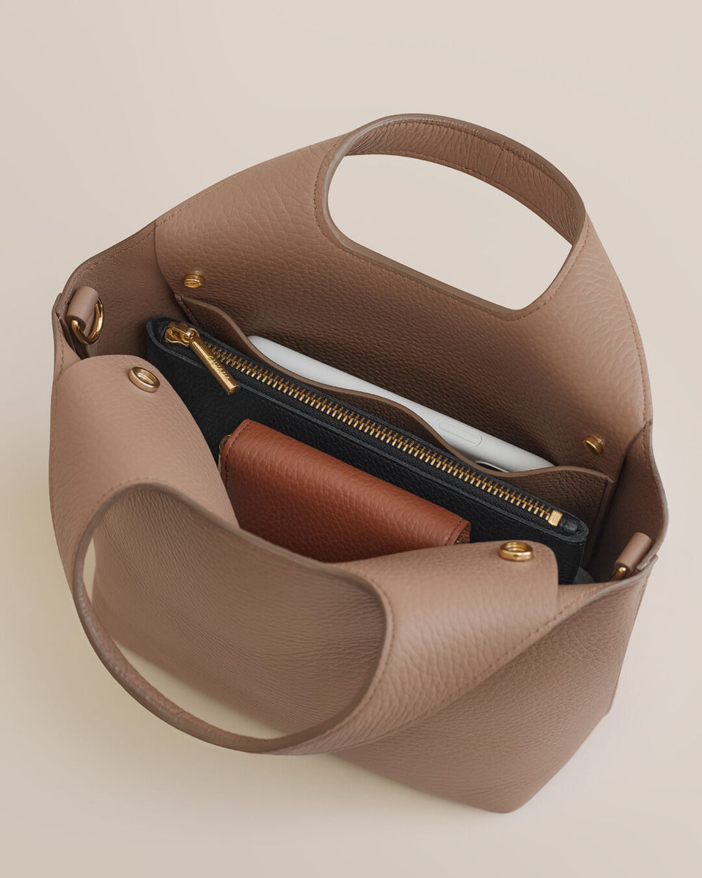 Handbag open showing contents with handles and zipper.