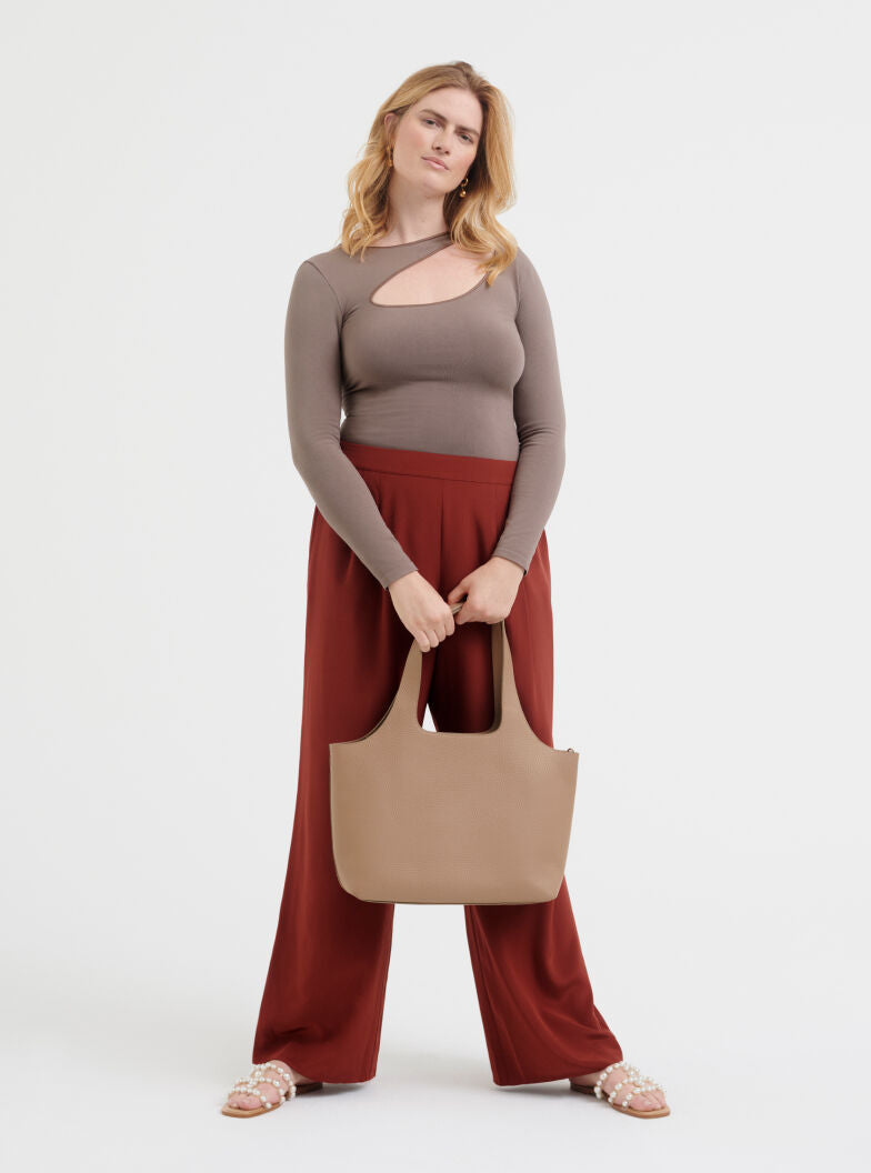 Stretch Long Sleeve Tee Woman standing with a handbag and wearing a long-sleeve top and wide-leg pants.