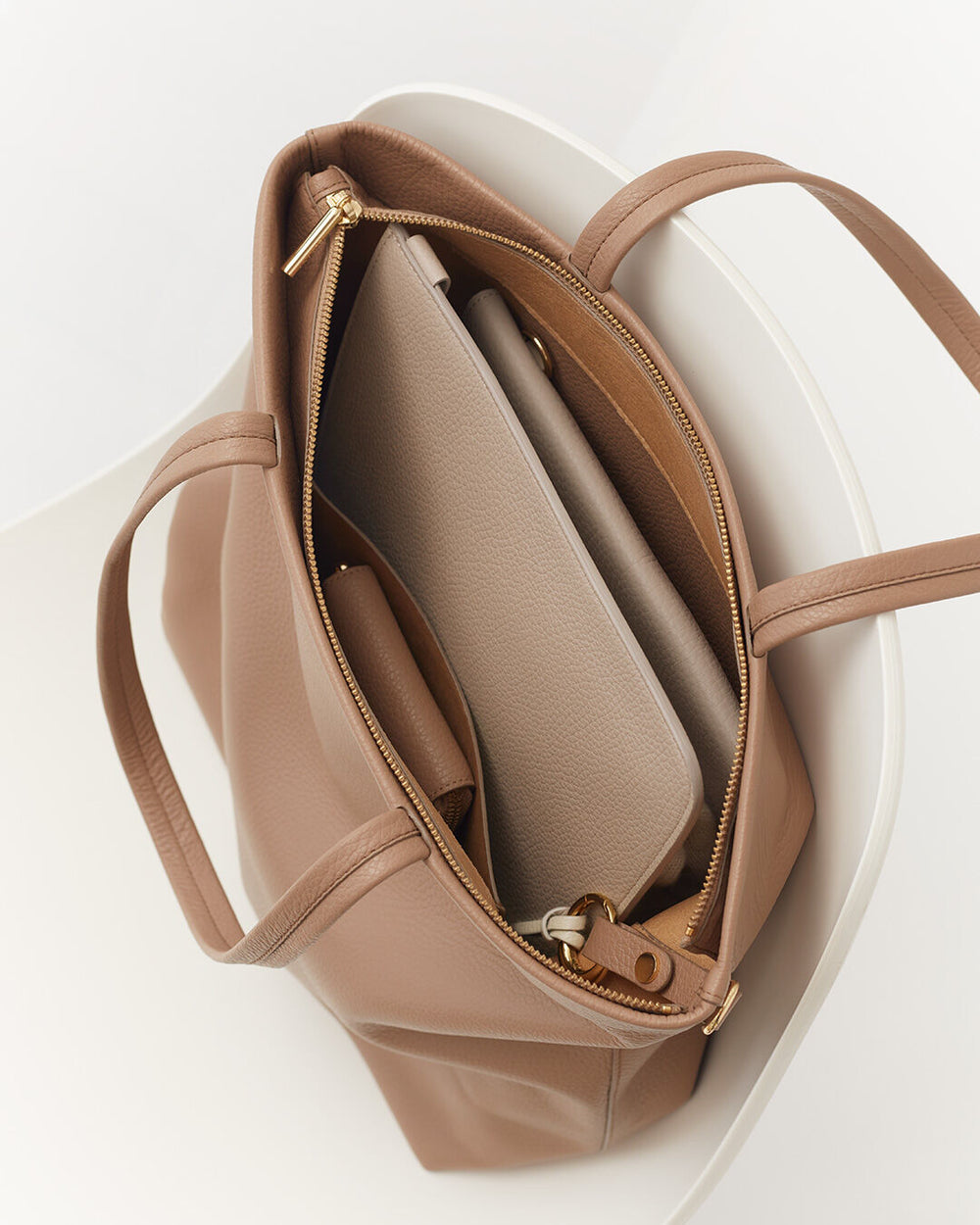 Tall Easy Zipper Tote Open handbag with zipper and compartments inside, positioned in a round container.