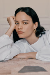 Woman resting her head on her hand, looking at the camera.