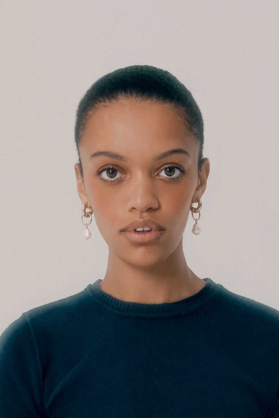 Woman facing forward with earrings and a sweater.