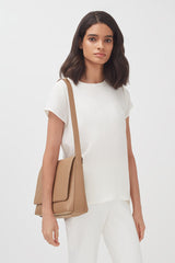 Woman standing with a shoulder bag.