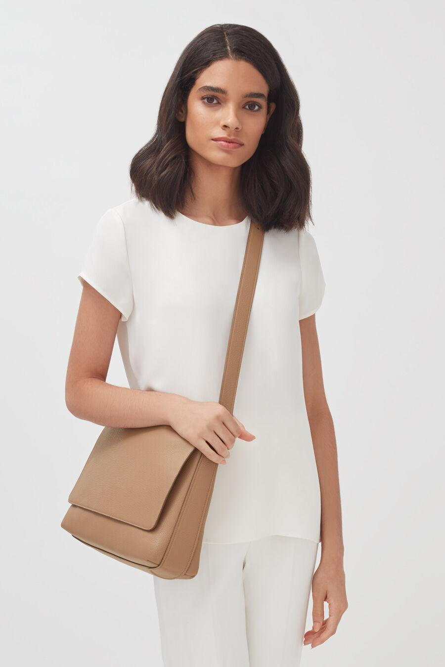 Messenger Bag 13-inch Woman standing with a shoulder bag, looking at the camera.