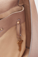 Close-up of a key hanging on a strap inside an open bag.
