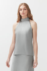 Woman in a sleeveless top and skirt standing against a plain background.