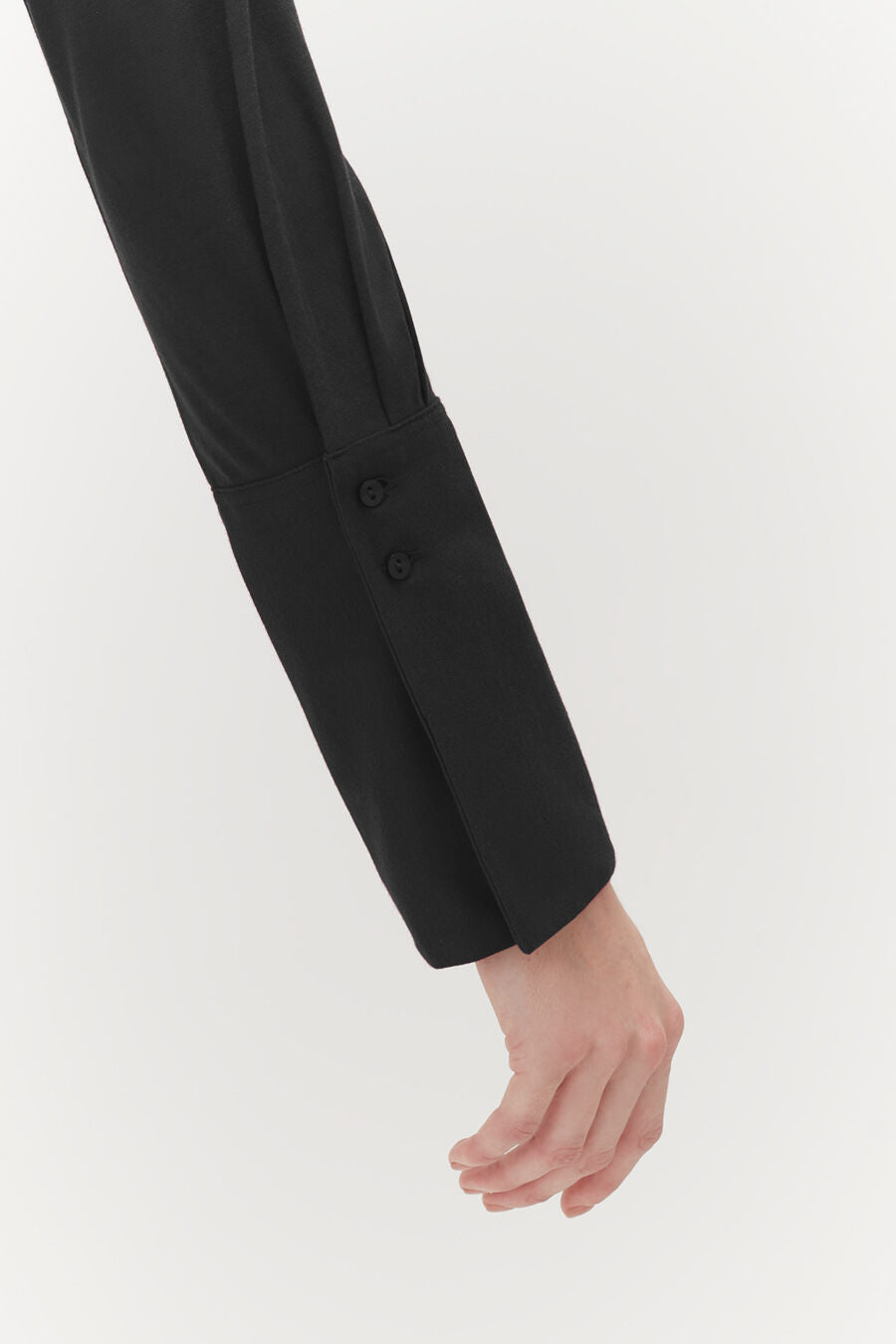 Organic Pima Shirt Close-up of a person's lower arm and hand, sleeve has buttons.