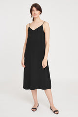 Woman standing in a sleeveless dress and sandals.