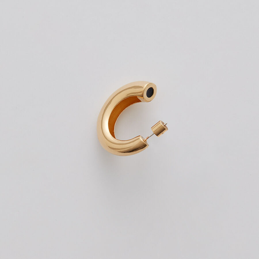 Single hoop earring with a gemstone on a plain background.